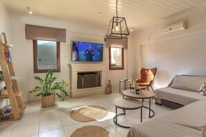 Una sala de estar con chimenea, televisor, sofá, sillón y una mesa de centro.