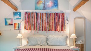 A bedroom with a bed, two bedside tables, a mirror, and wall art.