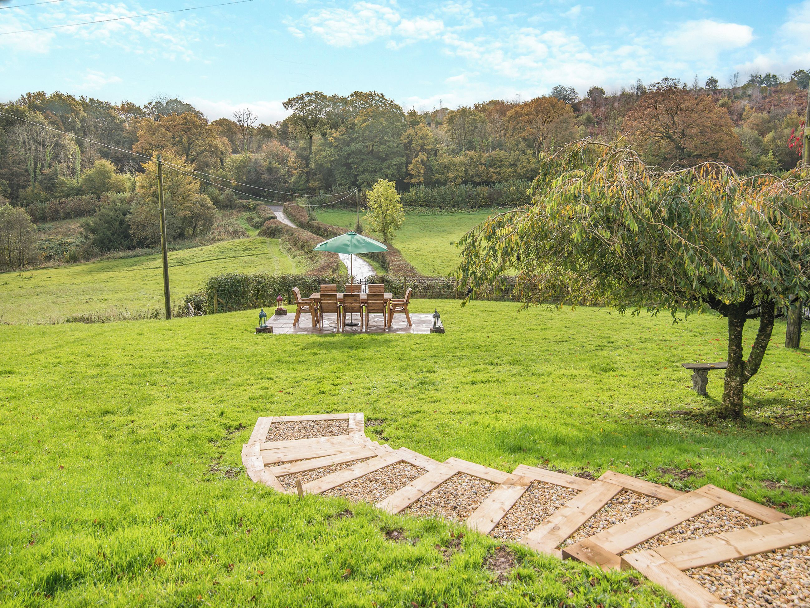 A grassy outdoor area with a wooden deck leading to a gazebo.