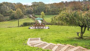 A grassy outdoor area with a wooden deck leading to a gazebo.