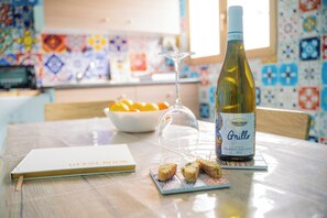 Una mesa con una botella de vino Grillo, una copa, un cuaderno y algunos alimentos.