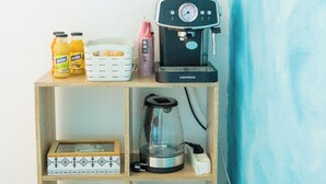 A wooden shelf with a coffee maker, juice bottles, a basket, and a box.