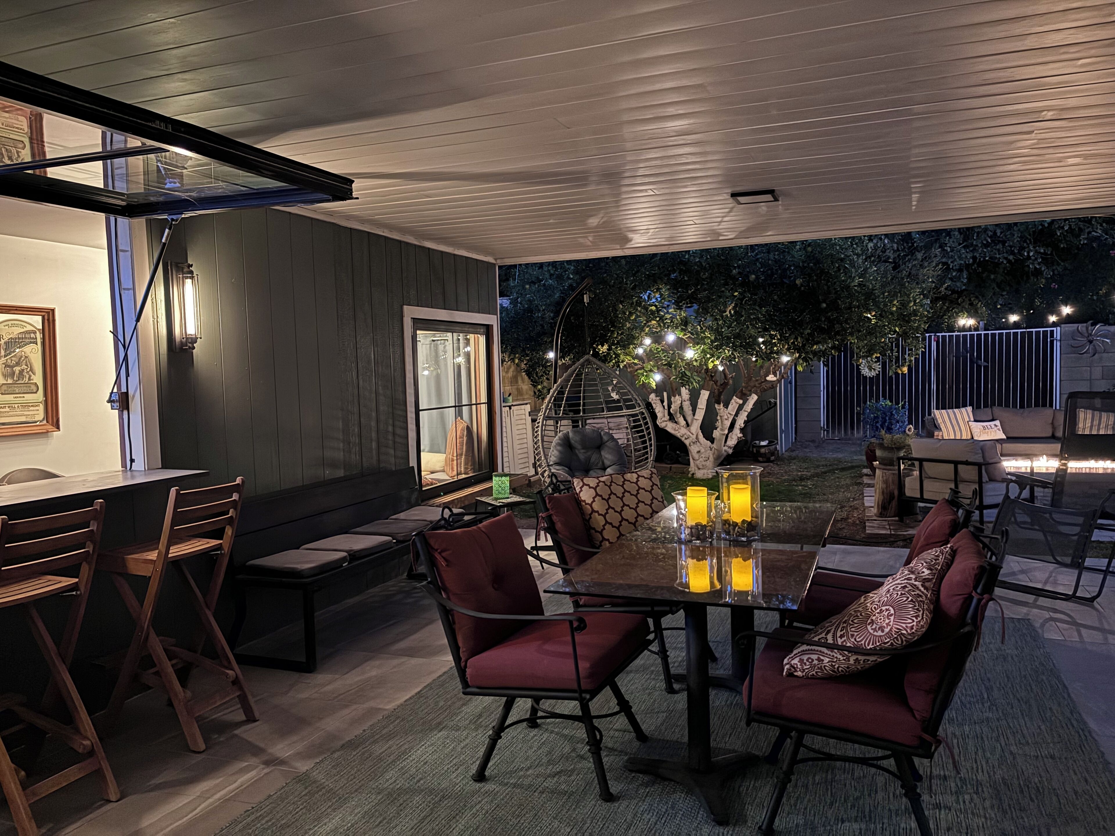 Een terras met een glazen tafel, rode zachte stoelen en een gezellige zithoek.