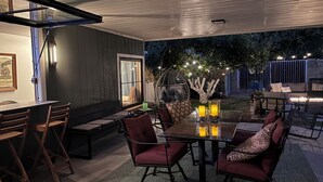 An outdoor dining area with a glass table, red cushioned chairs, and a cozy seating arrangement. - Beautifully restored charming MCM home in the heart of Tempe.  (Tempe)