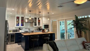 A modern kitchen with a central island, bar stools, and a ceiling fan. - Beautifully restored charming MCM home in the heart of Tempe.  (Tempe)