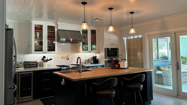 A modern kitchen with a central island, bar stools, and pendant lighting. - Beautifully restored charming MCM home in the heart of Tempe.  (Tempe)
