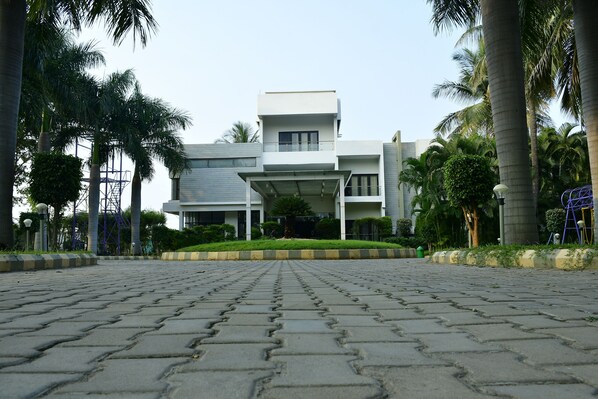 A modern building with a flat roof, large windows, and a central entrance. - Nijaguna Hotels and Resorts (Chamarajanagara)