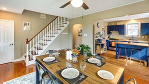 A dining area with a wooden table set for six, a ceiling fan, and a kitchen in the background. - The Blue House. 
A Family Beach House or Winter Getaway in Cape May (Cape May)