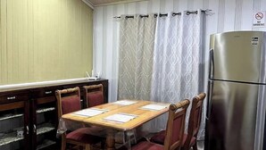 Ein Essbereich mit Holztisch und Stühlen, einem Kühlschrank und einer Küchenarbeitsplatte.