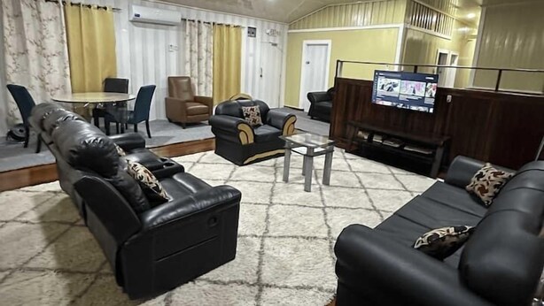 Ein Wohnzimmer mit einer schwarzen Ledersofa, einem kleinen Tisch und einem Fernseher.