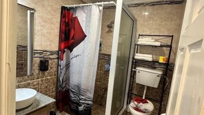 Un bany amb un rentapans blanc, un teló de dutxa, un vàter i una barra de tovalloles.