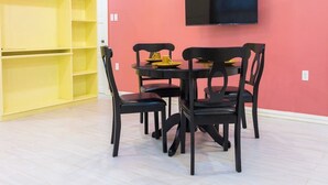 Un comedor con una mesa y sillas, un televisor montado en la pared y un estante amarillo.