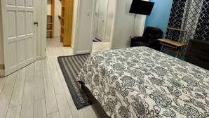 Un dormitorio con una cama, ventilador de techo, televisor y armario.