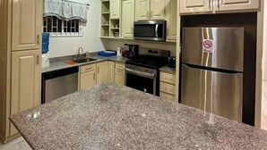 Una cocina con encimeras de granito, electrodomésticos de acero inoxidable y armarios de tonos claros.