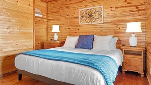 Een houten slaapkamer met een bed, nachtkastjes en een decoratief wandobject.