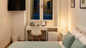 Una habitación de hotel con cama, escritorio, televisor y aire acondicionado.