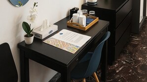 A hotel room with a desk, chair, mirror, flat-screen TV, and a bed with a view of the sea. - Colosseo Rooms (Rome)