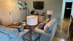 A living room with a sofa, a coffee table, a TV, and a lamp.