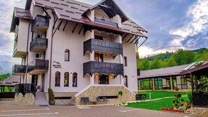 A multi-story hotel with balconies, a stone facade, and a covered outdoor seating area. - Bucovina Residence & SPA (Gura Humorului)