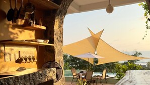 A cozy outdoor seating area with a stone fireplace, a fan, and a table with chairs. - Casa Jasmin Troncones (Troncones)