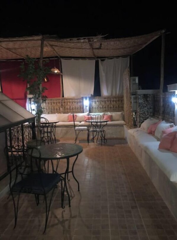 An outdoor seating area with a sofa, two tables, and chairs. - Charming Riad, 5 rooms (Marrakesh-Safi)