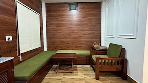 A cozy room with a wooden bench, a small table, and a green chair. - Zen Resort (West Kameng)