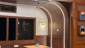 A room with a wooden floor, a table with a teapot, a wall-mounted light fixture, and a window with blinds. - Zen Resort (West Kameng)