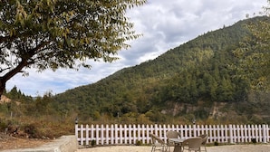 A gravel patio with a white picket fence and wicker chairs. - Zen Resort (West Kameng)