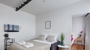 Un dormitorio moderno con una cama, una mesita de noche y un televisor montado en la pared.