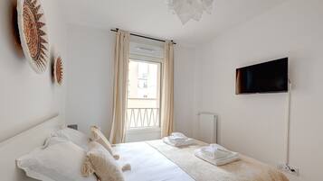 Ein Hotelzimmer mit Bett, Wandfernseher und einem fenster mit Vorhängen.