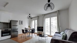 Un apartamento moderno con cocina, comedor y sala de estar. Cuenta con un ventanal grande, un sofá y un televisor.