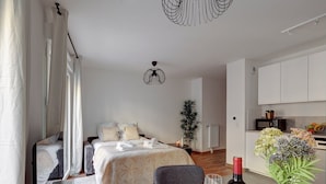 Un dormitorio moderno con cama, mesita de noche y un comedor con mesa para dos.