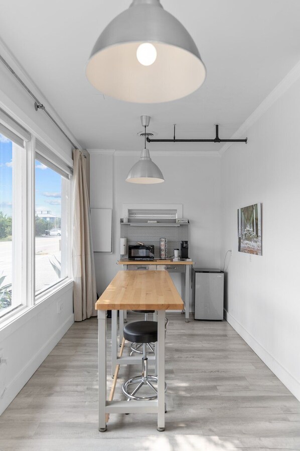 A modern kitchen with a wooden table and a pendant light.