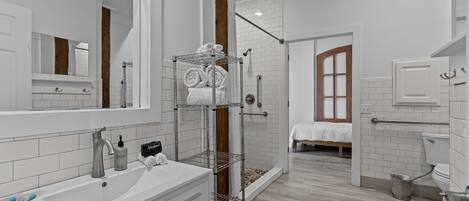 A modern bathroom with a white sink, mirror, and towel rack.