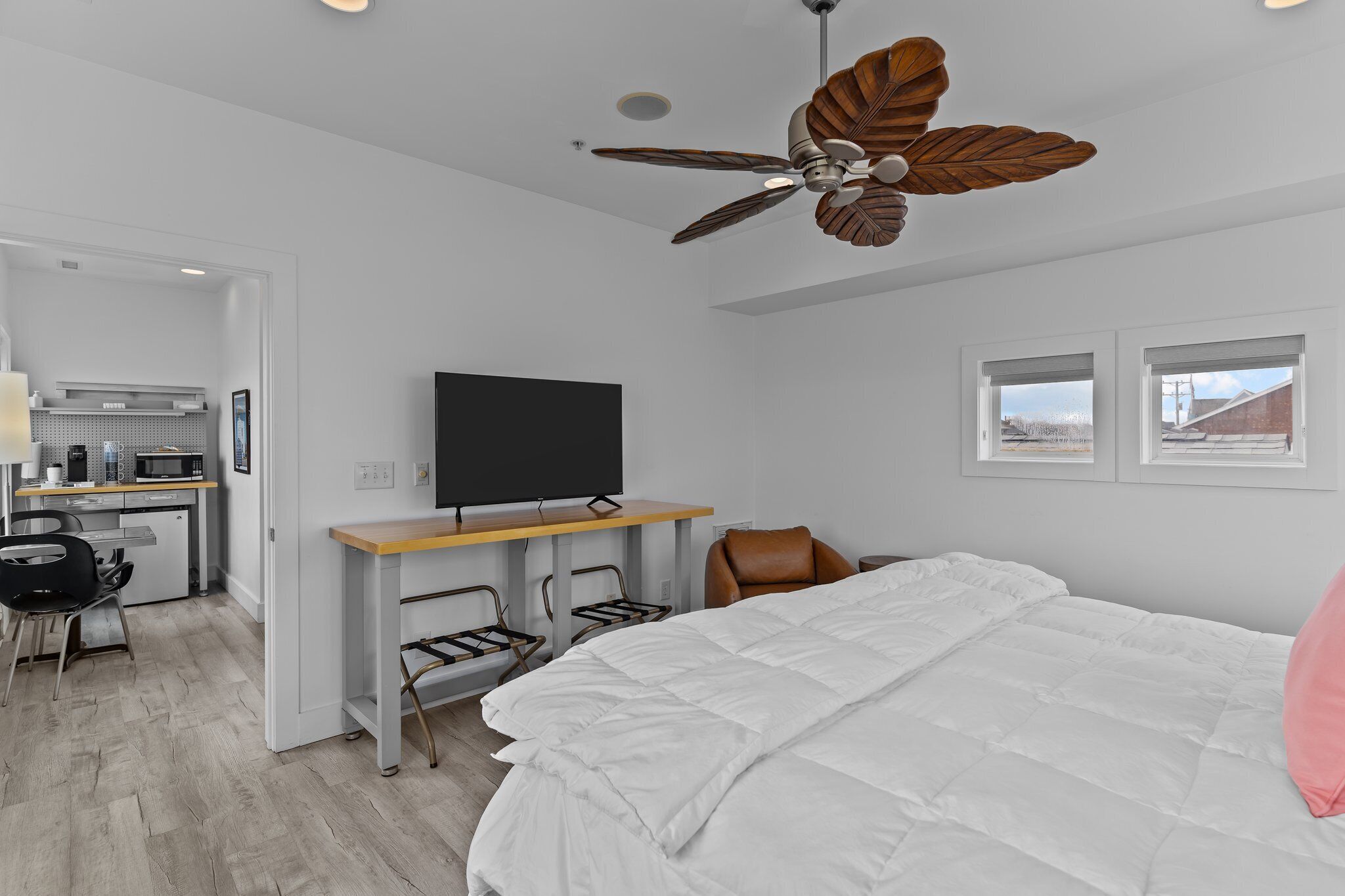 Une chambre d’hôtel moderne équipée d’un lit, d’un bureau avec un téléviseur à écran plat, d’un ventilateur de plafond et offrant une vue sur l’extérieur par une fenêtre.