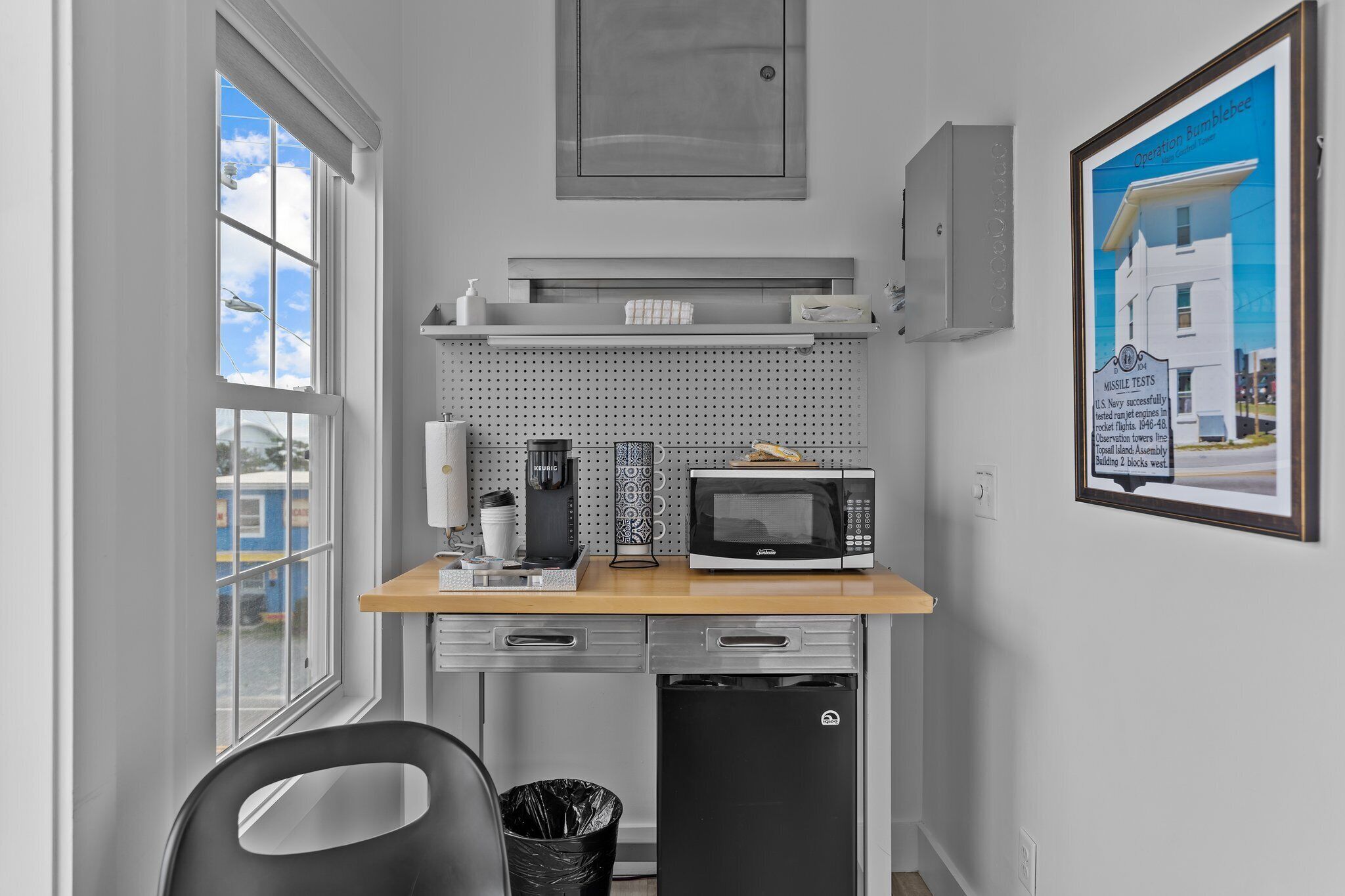 A compact kitchen with a microwave, coffee maker, and a small trash bin.