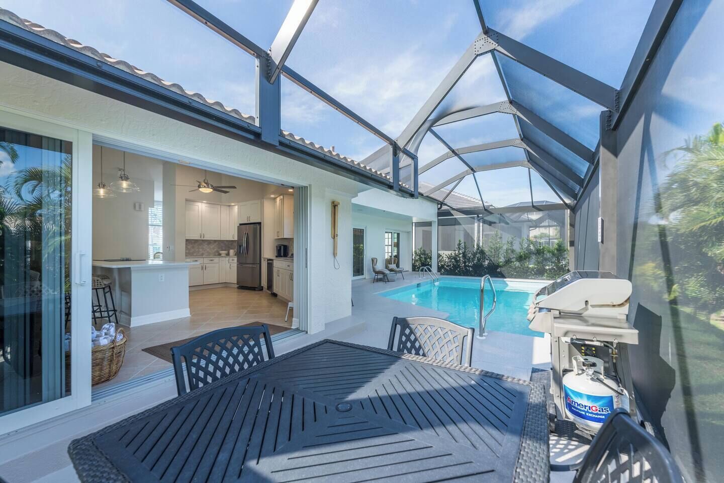 Un espace extérieur abrité comprenant une piscine, un barbecue et une table avec des chaises.