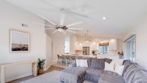 A modern living room with a sectional sofa, a dining area, and a kitchen. - Sea Suite (Marco Island)
