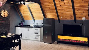 Cocina espaciosa con techos altos, vigas de madera, un refrigerador moderno y un comedor con mesa y sillas de madera.