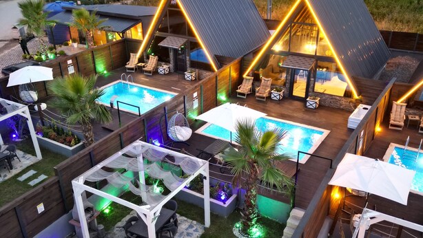 Un complejo turístico con varias piscinas, zonas de estar al aire libre y un patio bien iluminado.