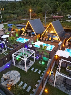 Un complejo turístico con varias piscinas, zonas de estar al aire libre y un patio bien iluminado.