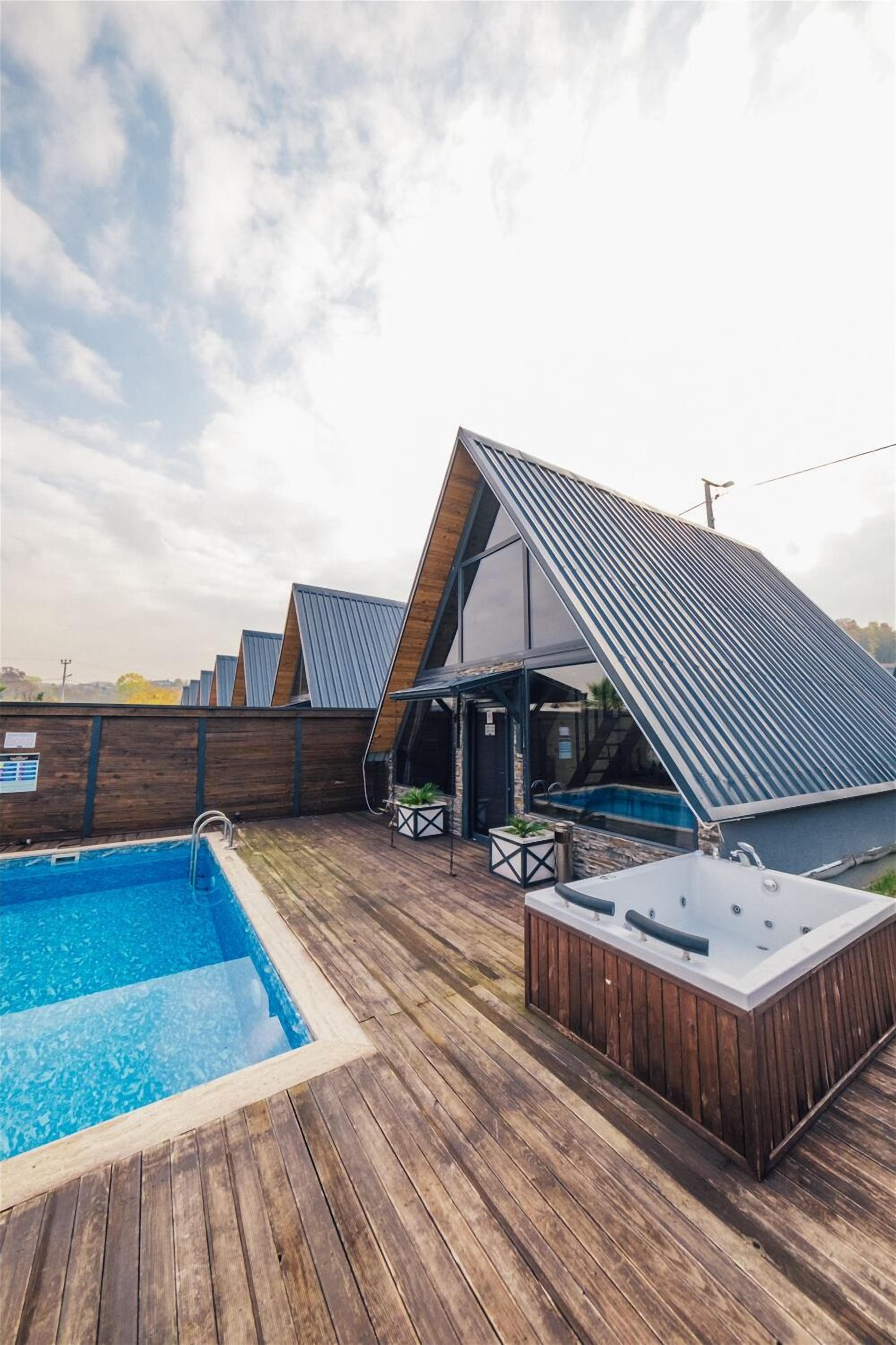 Um deck de madeira com piscina e banheira de hidromassagem.