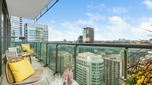 Ein Balkon mit Glasgeländer, Korbmöbeln und einem Tisch mit Flaschen und Gläsern.