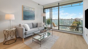 Ein modernes Wohnzimmer mit einer Couch, einem Couchtisch und einem großen Fenster mit Blick auf die Stadt.