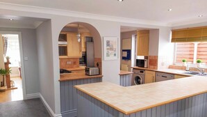A modern kitchen with a central island, built-in appliances, and a view to the dining area. - 3 bedroom accommodation in Conwy (Conwy)