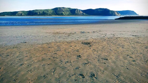 A beach with footprints in the sand and a distant view of hills. - 3 bedroom accommodation in Conwy (Conwy)