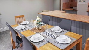 A dining area with a wooden table set for four, including plates, glasses, and cutlery. - 3 bedroom accommodation in Conwy (Conwy)