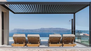 Ein Balkon mit drei Holz-Loungestühlen mit Blick auf das Meer.