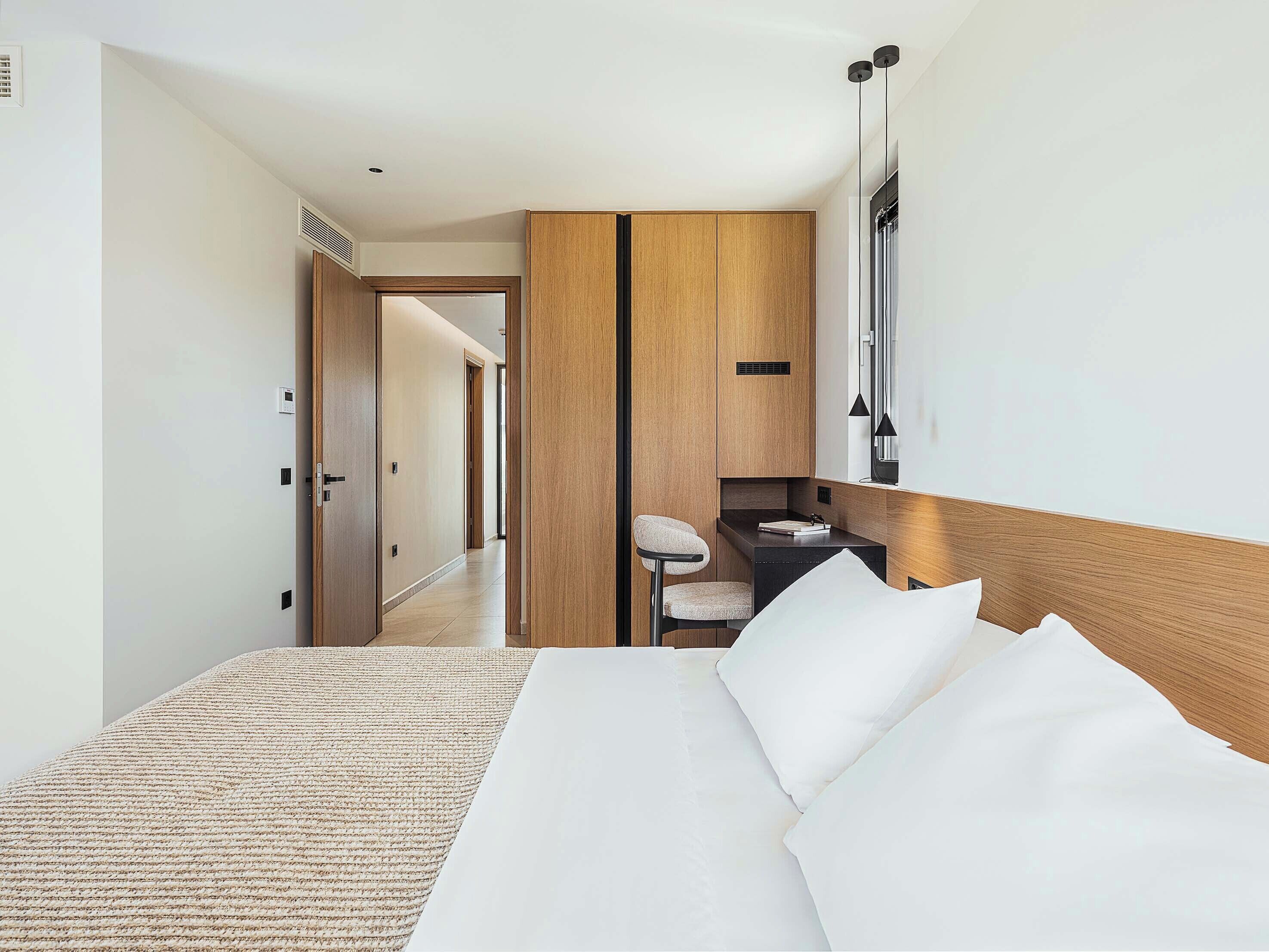 Une chambre d’hôtel moderne avec un grand lit, un petit bureau et une chaise.
