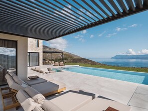 Una piscina al aire libre, sillones reclinables de piscina